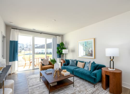 a living room with a blue couch and a sliding glass door at Fairmont at South Lake, Bowie, 20716