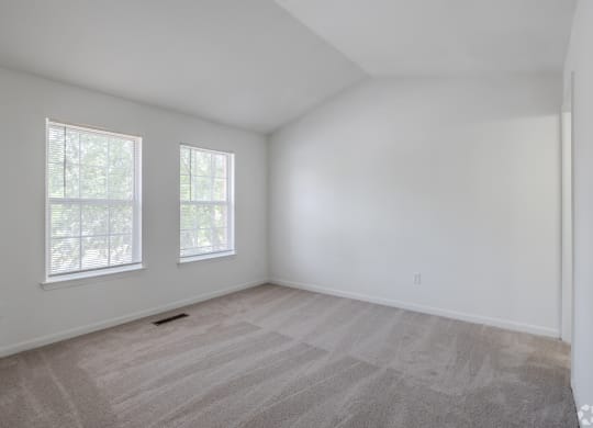the living room of a home with white walls and carpet at Greens at Stonecreek, Lithonia, Georgia