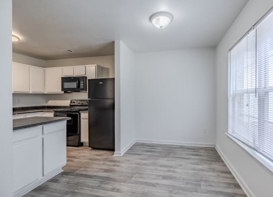 an empty kitchen with white cabinets and a black refrigerator and at Greens at Stonecreek, Lithonia