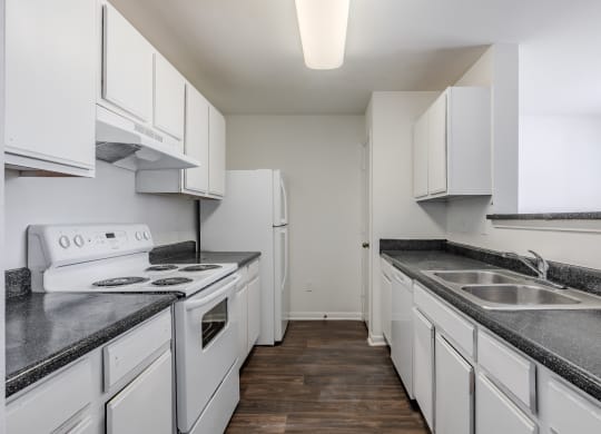 a kitchen with white cabinets and white appliances and granite counter tops at Greens at Stonecreek, Lithonia, 30038