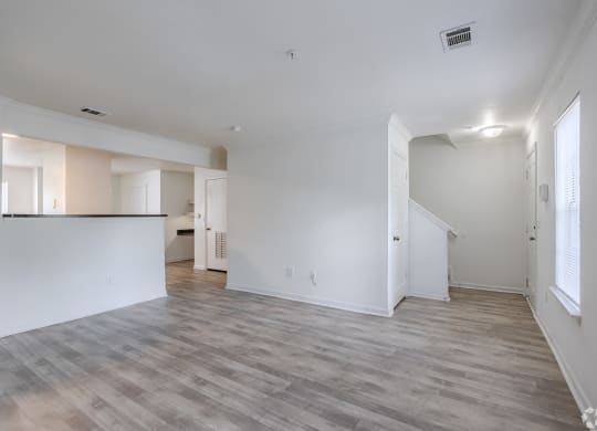 an empty living room and kitchen with white walls and wood flooring at Greens at Stonecreek, Lithonia, Georgia
