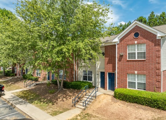 our apartments offer a spacious courtyard with trees and a brick building at Greens at Stonecreek, Lithonia, Georgia