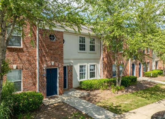 a brick building with a blue door and trees at Greens at Stonecreek, Lithonia, 30038