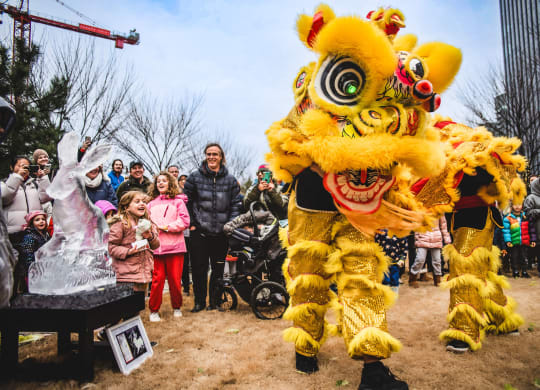 a person in a yellow lion costume standing in front of a crowd at Allied Harbor Point, Baltimore