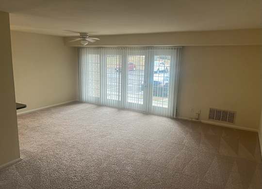 A room with a carpeted floor, a ceiling fan, and a sliding glass door at Shenandoah Station Apartments, Virginia 22172