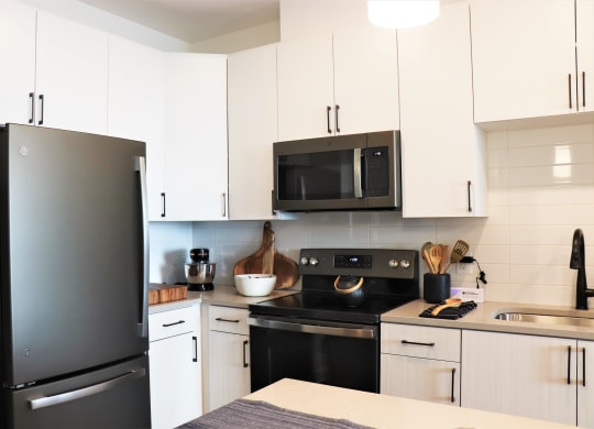 a kitchen with white cabinets and black appliances at Vyne One Loudoun, Ashburn, 20147