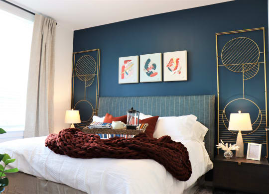 a bedroom with a blue wall and a white bed with a white comforter at Vyne One Loudoun, Ashburn, VA, 20147