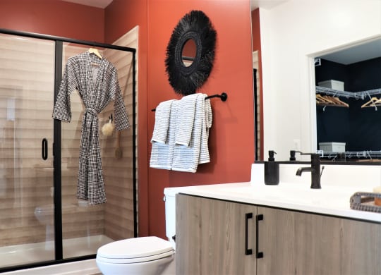 a bathroom with orange walls and a shower with a glass door at Vyne One Loudoun, Virginia