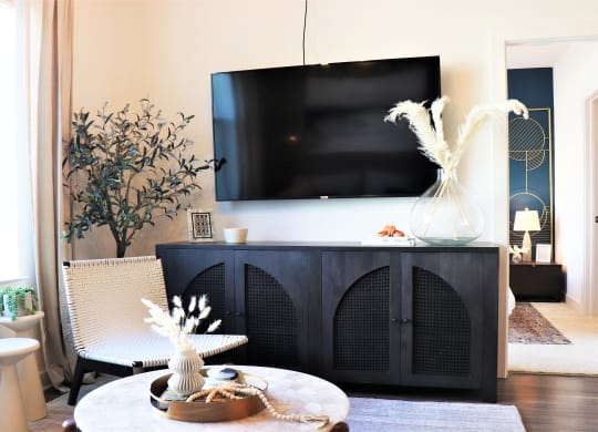 a living room with a tv on the wall and a table with a vase of flowers at Vyne One Loudoun, Ashburn, VA