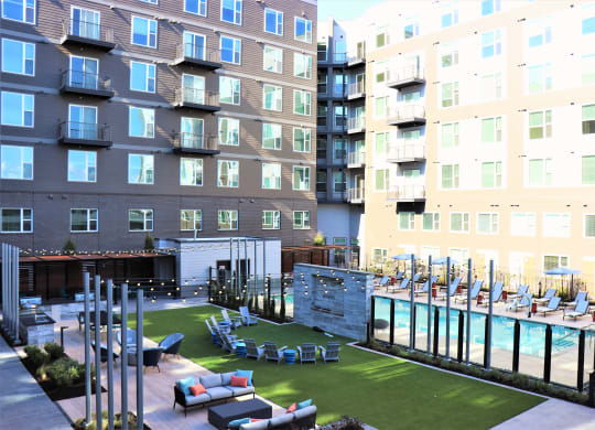 an outdoor lounge area with lounge chairs and a pool next to an apartment building at Vyne One Loudoun, Virginia