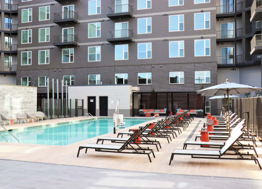 an outdoor pool with chaise lounge chairs and a building in the background at Vyne One Loudoun, Virginia, 20147