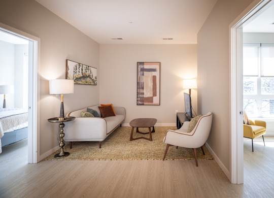 A living room with a white couch, a yellow chair, and a painting on the wall.