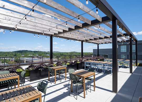A patio with tables and chairs under a wooden pergola.
