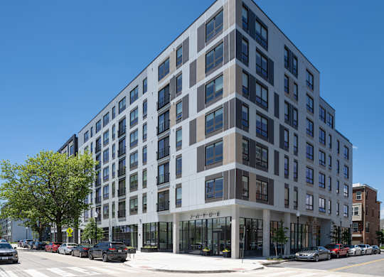 A modern multi-story building with a parking lot in front.