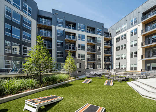 A modern apartment complex with a grassy courtyard and seating area at The Sully Apartments, Chantilly, VA
