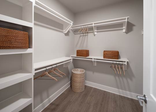A walk-in closet with white shelves and wooden hangers at The Sully Apartments, Chantilly