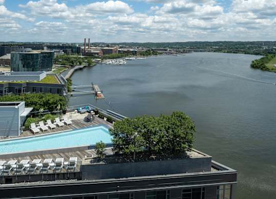 A view of a river from a high vantage point with a pool and trees in the foreground. at Dock 79, Washington, 20003