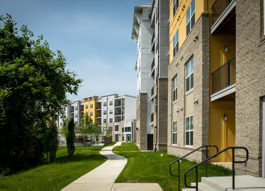 a pathway leads through a grassy area in front of an apartment building  at Woodmore Grand, Bowie