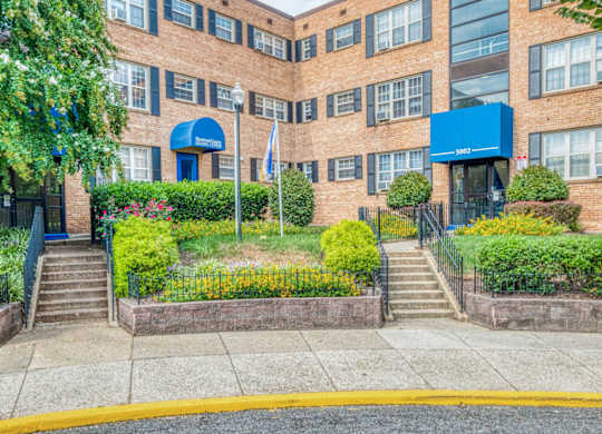 A building with a blue awning and a flag in front at Huntwood Courts Apartments, Washington, DC