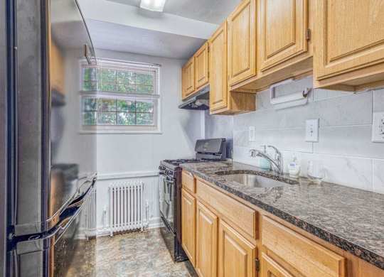 A kitchen with wooden cabinets and granite countertops at Huntwood Courts Apartments, Washington, 20019