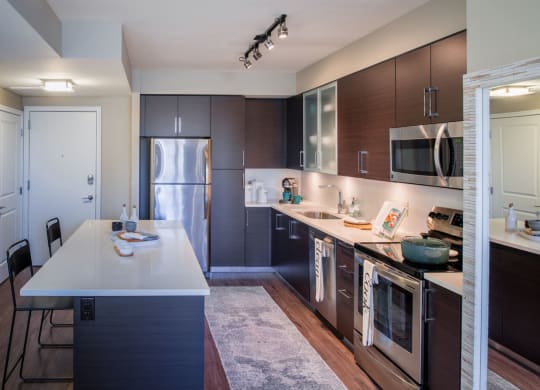 a kitchen with dark wood cabinets and white countertops at The Acadia at Metropolitan Park, Arlington, VA, 22202