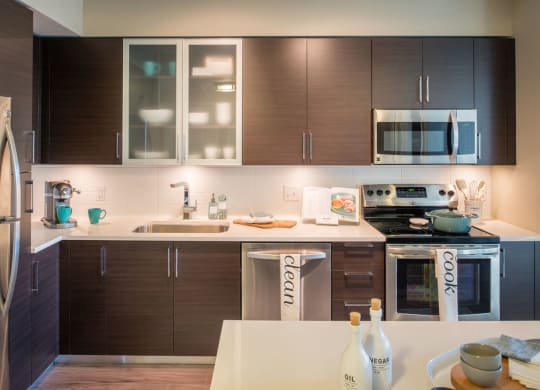 a modern kitchen with dark wood cabinets and white countertops at The Acadia at Metropolitan Park, Virginia