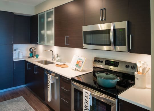 a kitchen with a stove top oven next to a sink at The Acadia at Metropolitan Park, Arlington