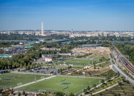 an aerial view of a football field in a city with a river in the background at The Acadia at Metropolitan Park, Arlington, Virginia