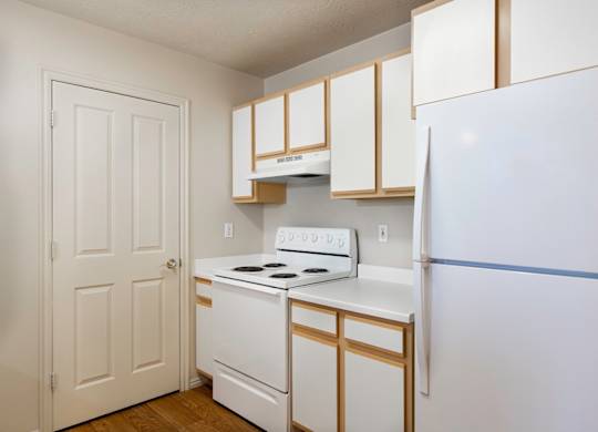 A white and gold kitchen with a white fridge. at Bluffs Apartments, Bluffdale, Utah