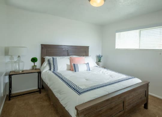 A bedroom with a bed, nightstand, and window.at Country Woods, Ogden Utah  