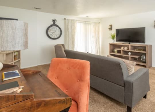A living room with a grey couch, a wooden coffee table, and a television.at Country Woods, Ogden, UT 84401  