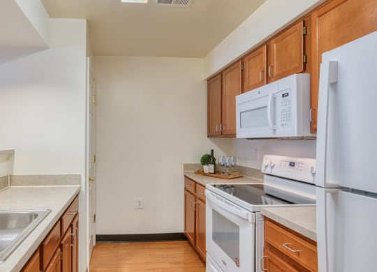 a kitchen with white appliances and wooden cabinets at North Market South Carroll, Frederick Maryland