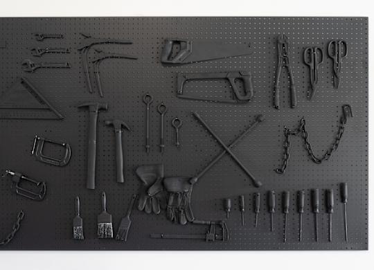 A collection of various tools is displayed on a pegboard.
