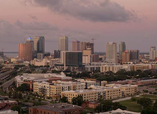 A cityscape with buildings of various heights and a cloudy sky.