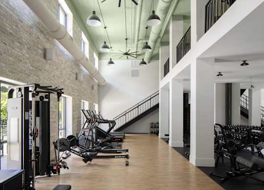 A gym with a row of treadmills and a row of stationary bikes.