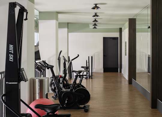 A gym with exercise equipment and mirrors on the wall.