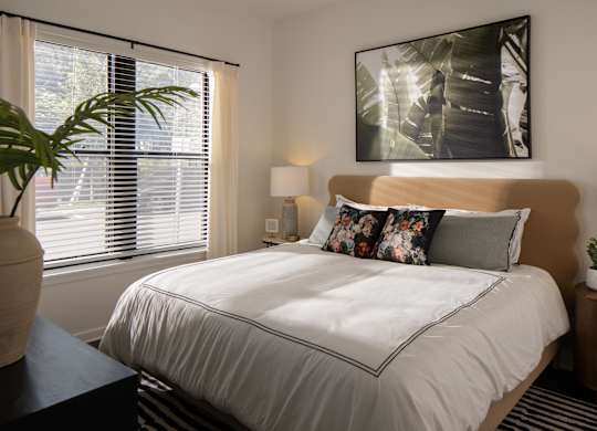 A bedroom with a large bed and a painting on the wall.
