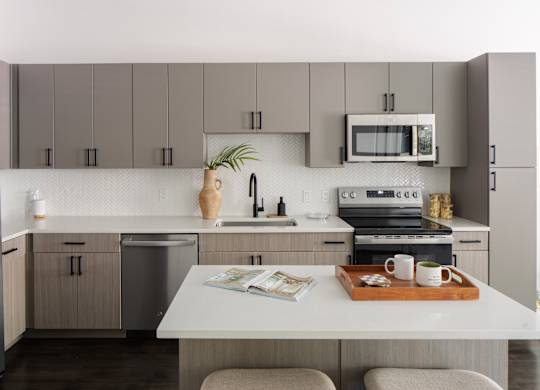 A kitchen with a white countertop and grey cabinets.