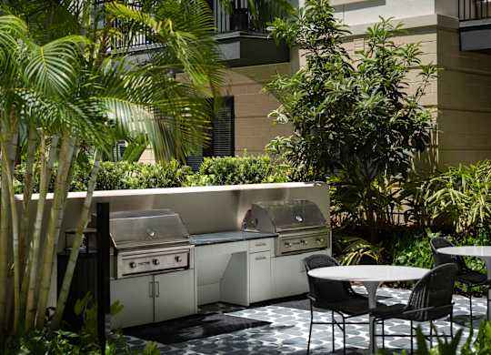 A patio with a table and chairs and a grill.