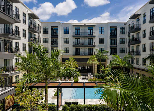 A view of a pool surrounded by palm trees and apartment buildings.