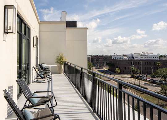 A balcony with chairs and a table is overlooking a city street.