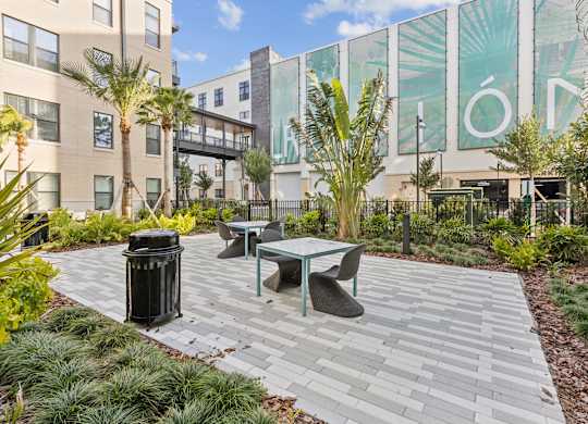 A patio with a table and chairs surrounded by plants.