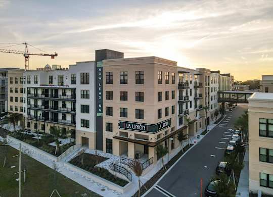 A street view of a residential area with apartment buildings and a crane in the background.