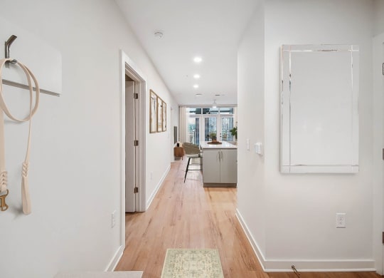 a long hallway with white walls and a door to a kitchen at Hawkins Press Apartments, Charlotte