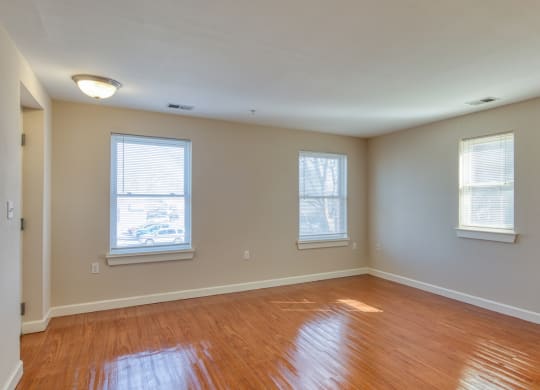 an empty living room with wooden floors and three windows at North Market South Carroll, Maryland