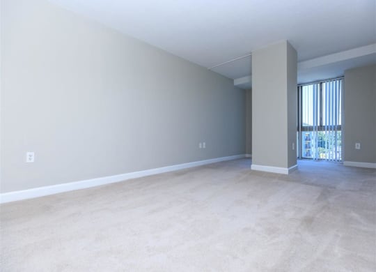 an empty living room with a sliding glass door and a balcony at The Gramax, Silver Spring, Maryland