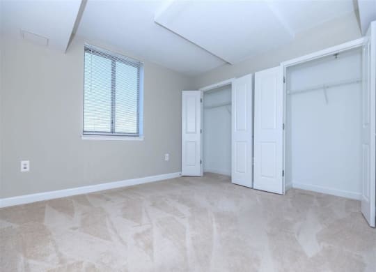 an empty bedroom with a closet and a window at The Gramax, Silver Spring, 20910