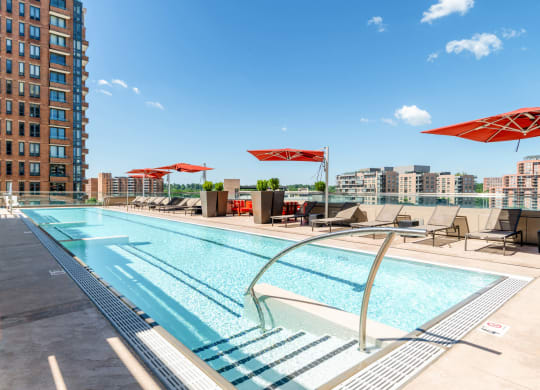 a swimming pool with chairs and umbrellas on a sunny day at a hotel at The Acadia at Metropolitan Park, Arlington, Virginia