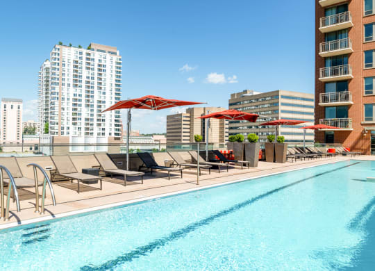 a swimming pool with chairs and umbrellas on top of a building at The Acadia at Metropolitan Park, Arlington, 22202