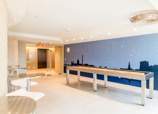 a game room with a pool table and a wall mural of the city skyline at The Acadia at Metropolitan Park, Arlington, Virginia